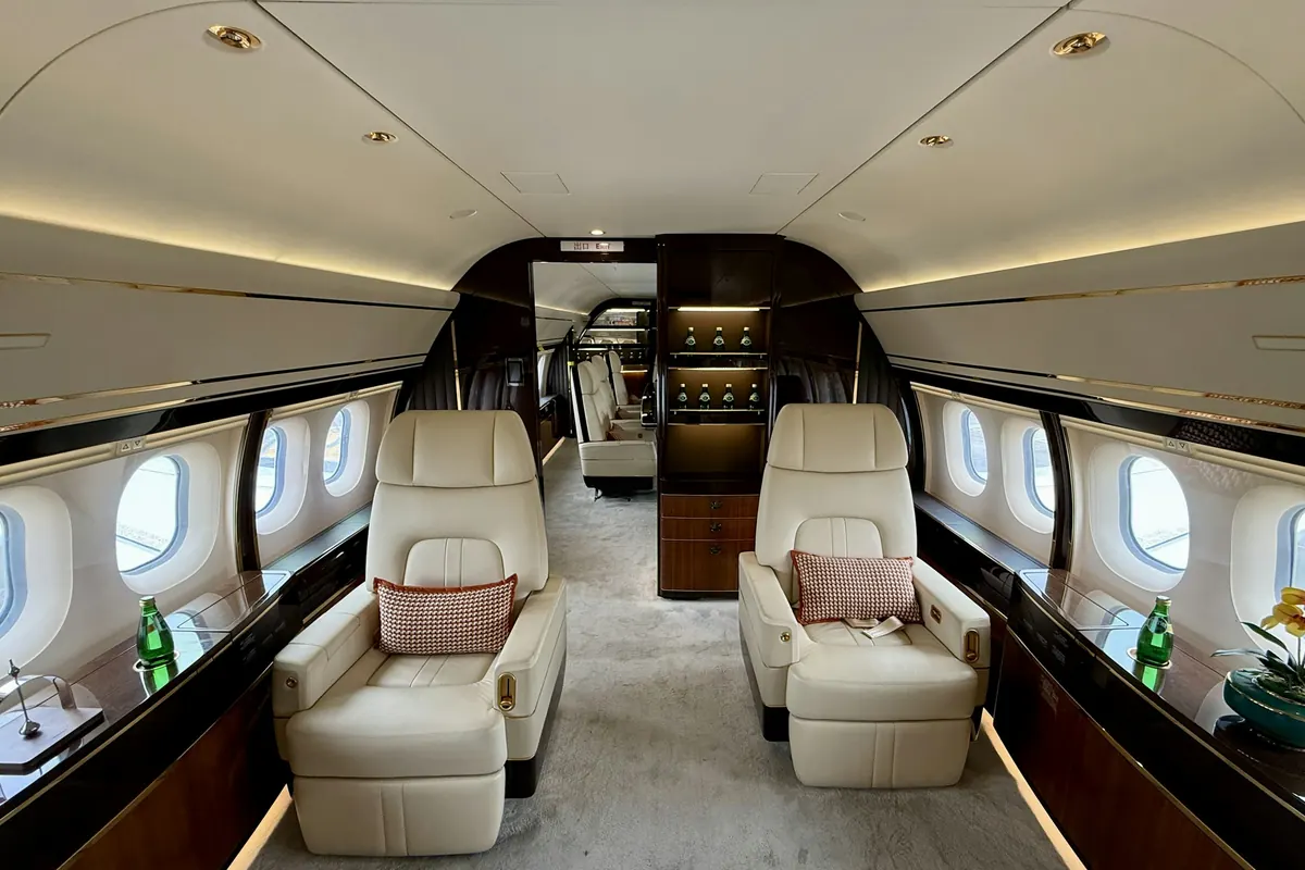 Wide cabin of a large private jet with club seats and wood veneer