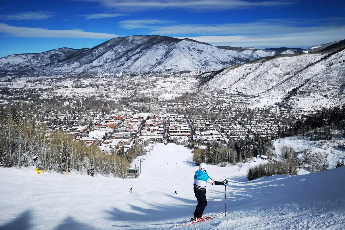 Skier above the town of Aspen with snow-covered mountains